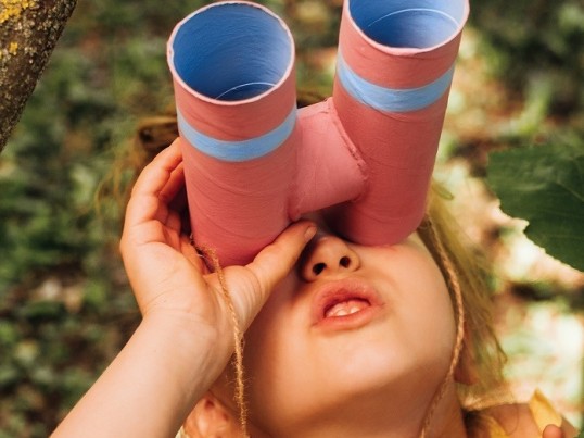 Mädchen mit Fernglas in einem Baum