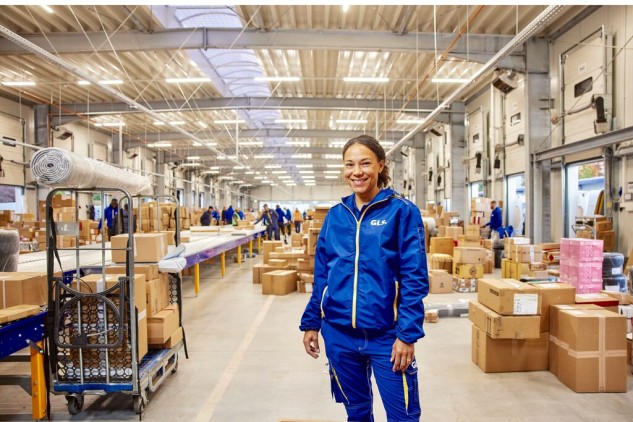Logistics employee in an industrial warehouse managing packages and shipments in a distribution center with boxes and conveyor belt