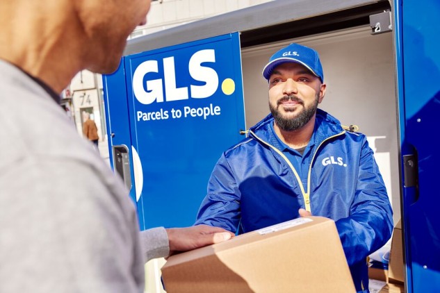 Courier delivering a package to a customer at a GLS pickup point next to a parcel locker station