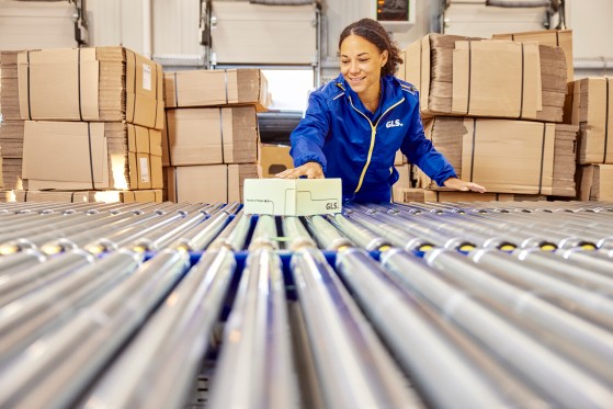 A GLS employee slides a parcel through the parcel counter