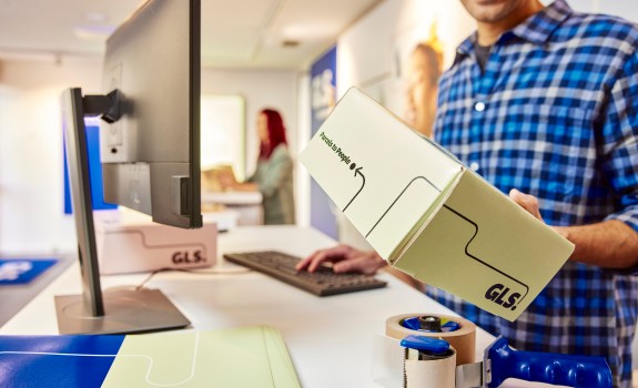 GLS employee holds GLS parcel on his hands at GLS Parcelshop