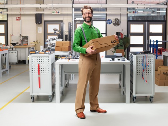 homme tenant un colis GLS dans un atelier technique moderne
