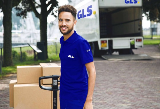 Courrier GLS souriant déchargeant la palette du transport 