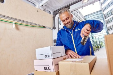 GLS driver scans a parcel in the back of a delivery van. 